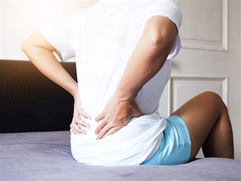 Women Suffering With Back Pain And Waist Pain Sitting On Bed Premium
