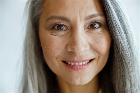 Attractive Silver Haired Woman In Beige Shirt Touches Cheek On Light