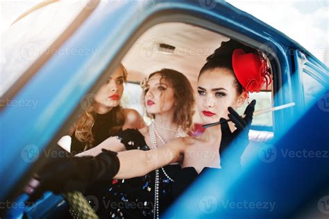Three Young Girl In Retro Style Dress Seat On Old Classic Vintage Car