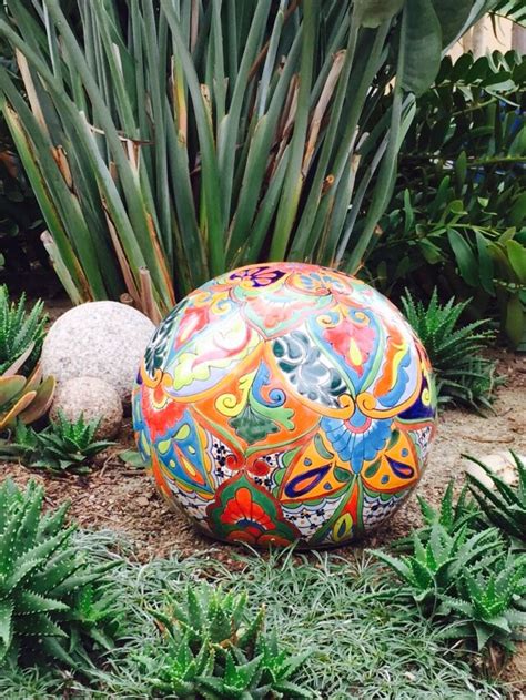 An Artisticly Painted Ball Sits In The Middle Of Some Plants And Rocks