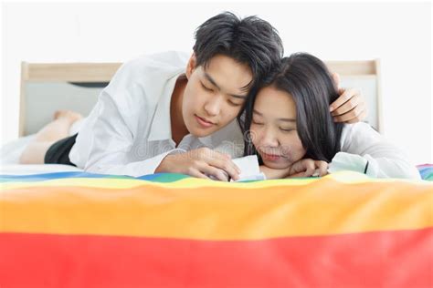 Lgbtq Couple Lovers A Handsome Girl As A Man Or Femme Girl Laying On A Bed With The Rainbow