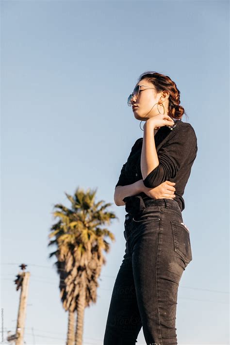 Young Female Wearing Black Clothes Standing Outdoors By Palm Tree By