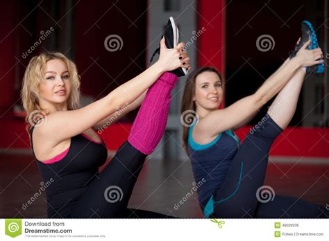 twee glimlachende meisjes doen uitrekkende oefeningen in geschiktheidscentrum stock foto image