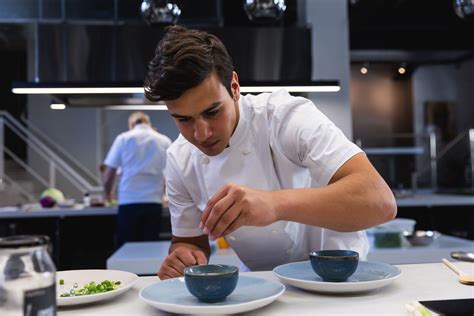 Young Male Chef Garnishing Food At Restaurant Kitchen