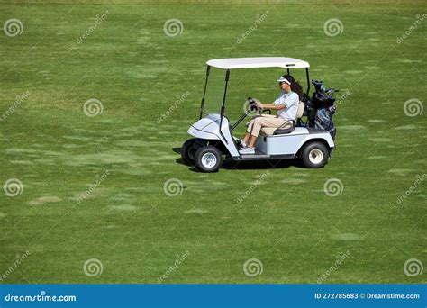 View At Young Woman Driving Golf Cart On Green Field In Sunlight Stock