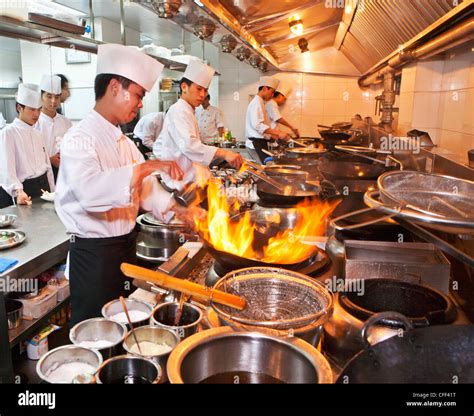 chefs preparing chinese cuisine in woks in the modern kitchen of a chinese restaurant beijing
