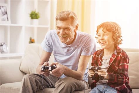Grandfather And Grandson Are Playing Video Games At Home Stock Photo