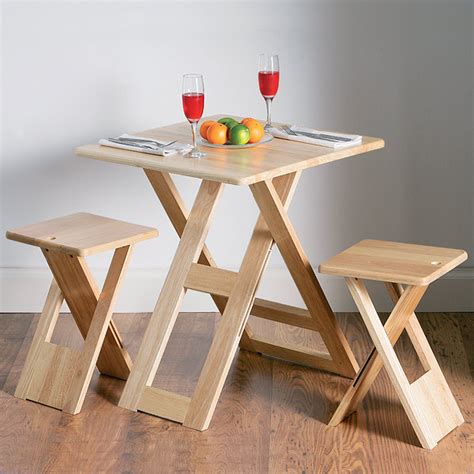 It is a set that includes four folding wood chairs with natural finish. Folding Dining Table Set | Drinkstuff