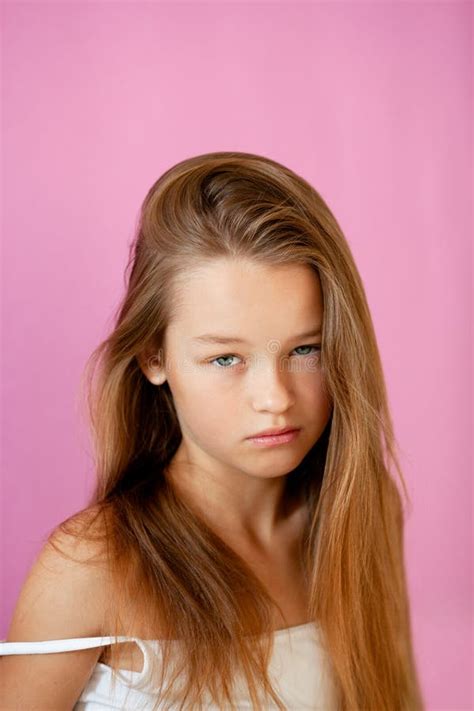 Portrait Of A Gentle 9 Year Old Long Haired Girl In A Light T Shirt Against A Lilac Wall Stock