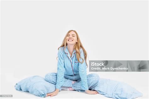 Schönes Mädchen Im Pyjama Auf Dem Bett Sitzend Mit Kissen In Den Händen Auf Weißem Hintergrund