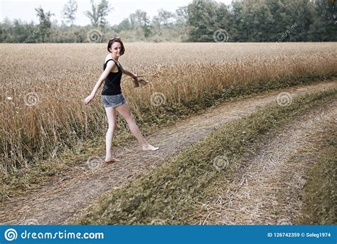 ragazza che cammina a piedi nudi sulla strada a terra attraverso il campo e la foresta sul