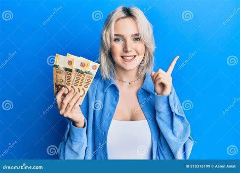 Young Blonde Girl Holding Hungarian Forint Banknotes Smiling Happy Pointing With Hand And Finger