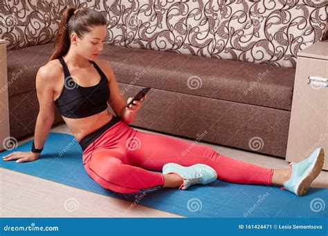 Indoor Shot Of Beautiful Caucasian Sporty Woman With Smartphonein Hands