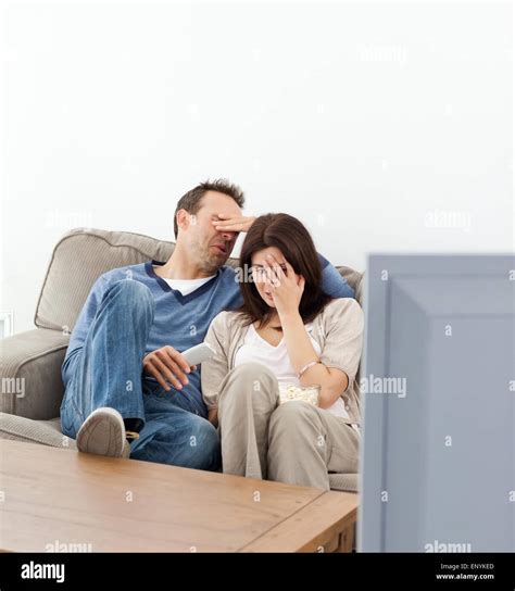 Scared Couple Hiding Their Faces While Watching A Horror Movie Stock