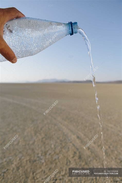 Male Hand Pouring Water From Bottle In Landscape Of Black Rock Desert