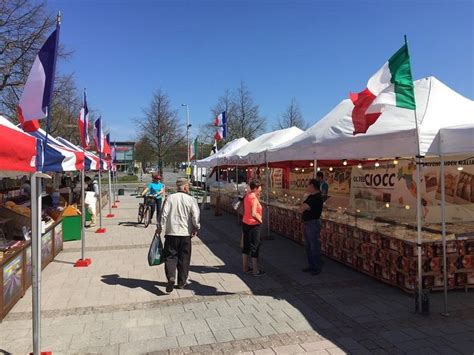 People Are Walking Around An Outdoor Market With Flags On The Walls And