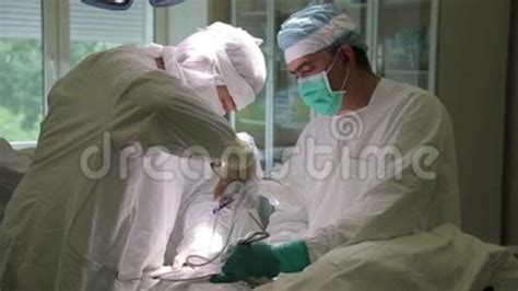 Two Doctors In Protective Clothing Performing Surgery Use Sterilized