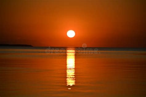 El Sol Se Pone En Una Tranquila Superficie Reflejada Del Mar Y Un Barco