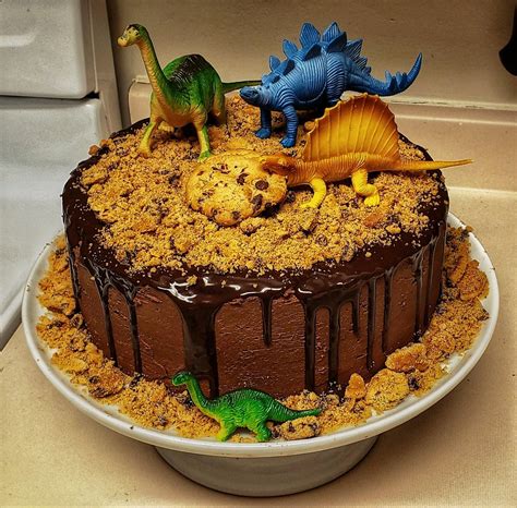 A Birthday Cake With Chocolate Frosting And Dinosaurs On Top