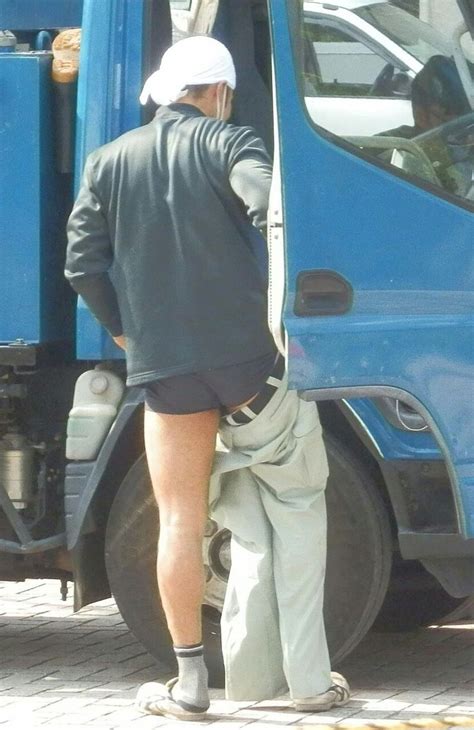 A Man Standing In Front Of A Blue Truck With His Back Turned To The Camera