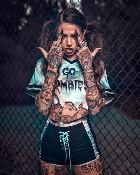 A Woman With Tattoos On Her Arms And Hands Covering Her Face While