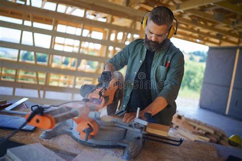 Construction Worker Working With Eletric Saw Inside Wooden Construction