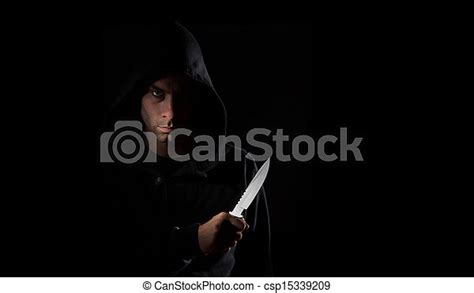 A Dangerous Hooded Man Standing In The Dark And Holding A Shiny Knife