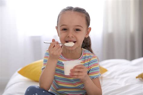Cute Little Girl Eating Tasty Yogurt On Bed Stock Photo Image Of