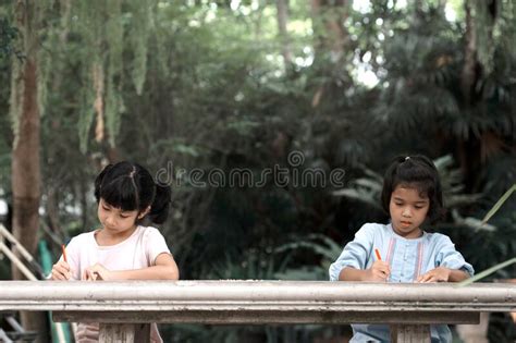 Two Asian Girls Kids Sitting And Painting In The Garden Stock Image