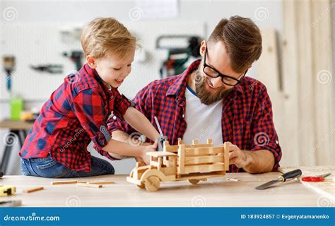 Cheerful Man With Kid Making Wooden Toys In Workshop Stock Image