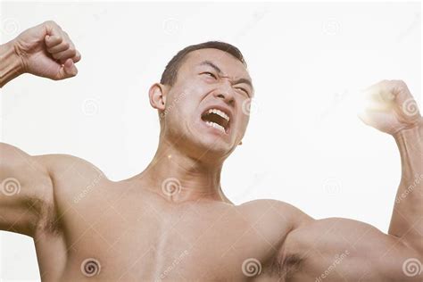 Front View Of Shirtless Angry Roaring Young Man Flexing His Muscles