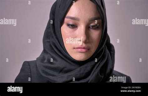 Young Sad Muslim Girl In Hijab Is Watching Down And At Camera Grey