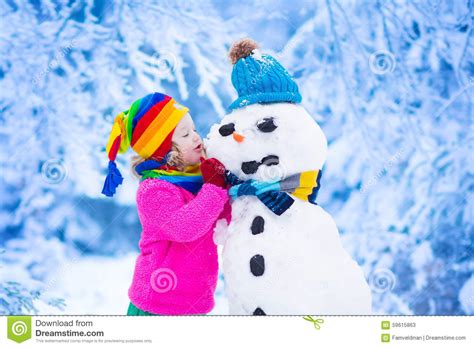 Little Girl Building A Snow Man In Winter Stock Image