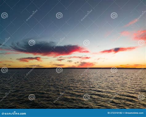 A Sunset Over The Water With A Pink Cloud Stock Photo Image Of