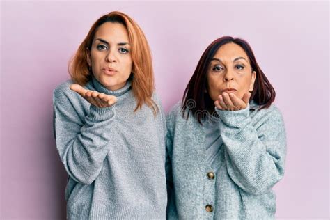 Latin Mother And Daughter Wearing Casual Clothes Looking At The Camera Blowing A Kiss With Hand