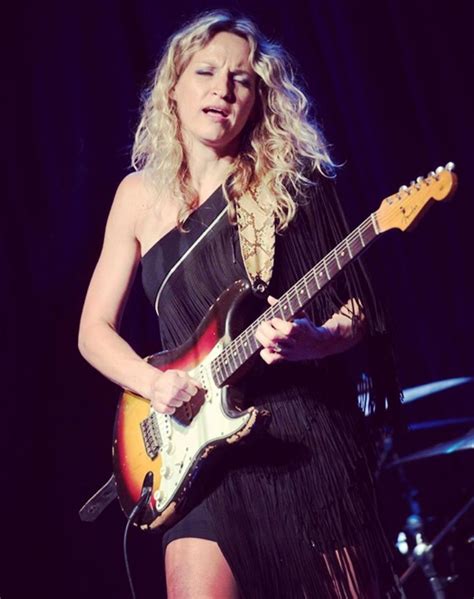 A Woman In A Black Dress Playing An Electric Guitar