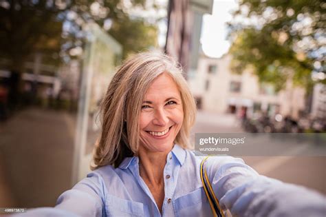 Smiling Mature Woman On A City Street Taking Fun Selfie High Res Stock