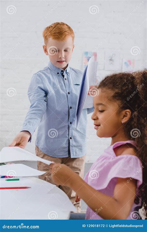 Selective Focus Of Multicultural Preschoolers With Papers Stock Photo