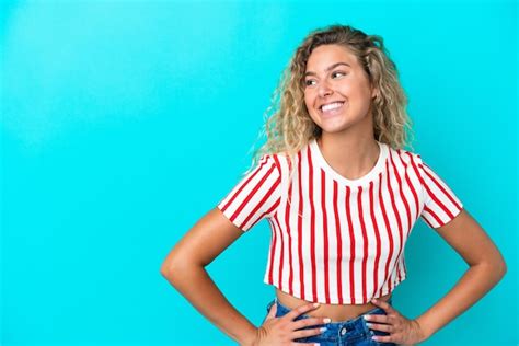 Premium Photo Girl With Curly Hair Isolated On Blue Background Posing With Arms At Hip And Smiling