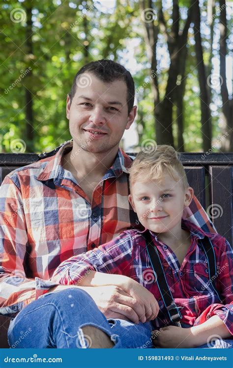 Handsome Dad And Son Are Sitting On A Bench In The Park Stock Image