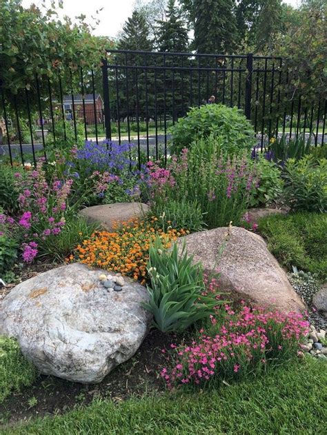A Garden With Rocks And Flowers In The Foreground Surrounded By A