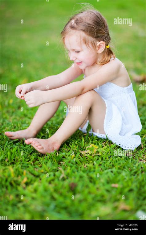 Adorable Little Girl Sitting On A Grass Stock Photo Alamy