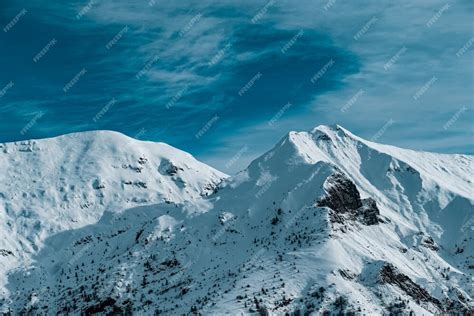 Free Photo Panoramic Shot Of Snow Covered Mountain Peaks Under Cloudy