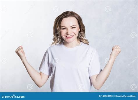 Portrait Of Overjoyed Beautiful Woman Clenches Fists With Happiness Poses Against White