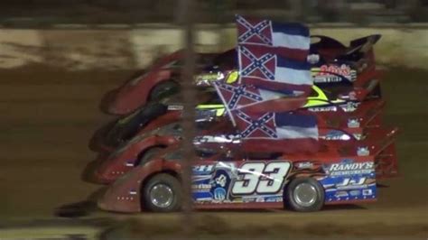 A Car That Is Sitting In The Dirt With Some Flags On Its Back