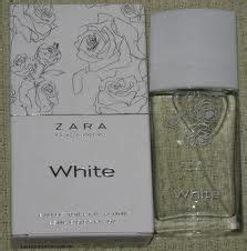 A Bottle Of Zara White Perfume Sitting Next To A Box On A Cloth Covered