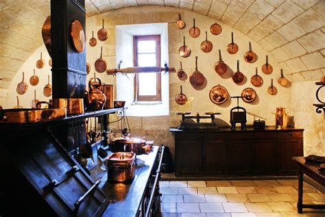 An Old Fashioned Kitchen With Pots And Pans Hanging On The Wall