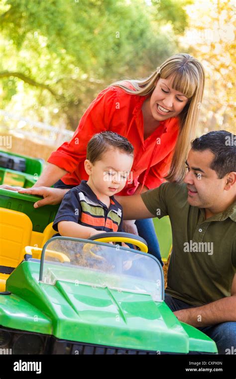 Happy Young Mixed Race Boy Enjoys A Toy Tractor While Parents Look On