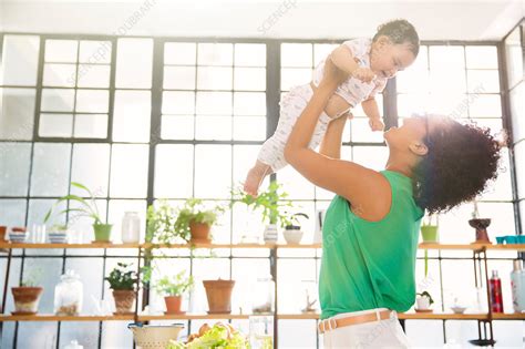 mother lifting her daughter overhead stock image f015 1744 science photo library