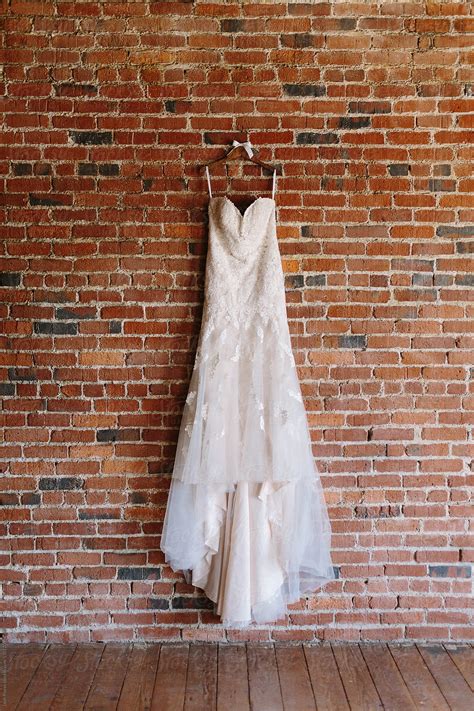Beautiful Lace Wedding Dress Hanging On Brick Wall By Stocksy